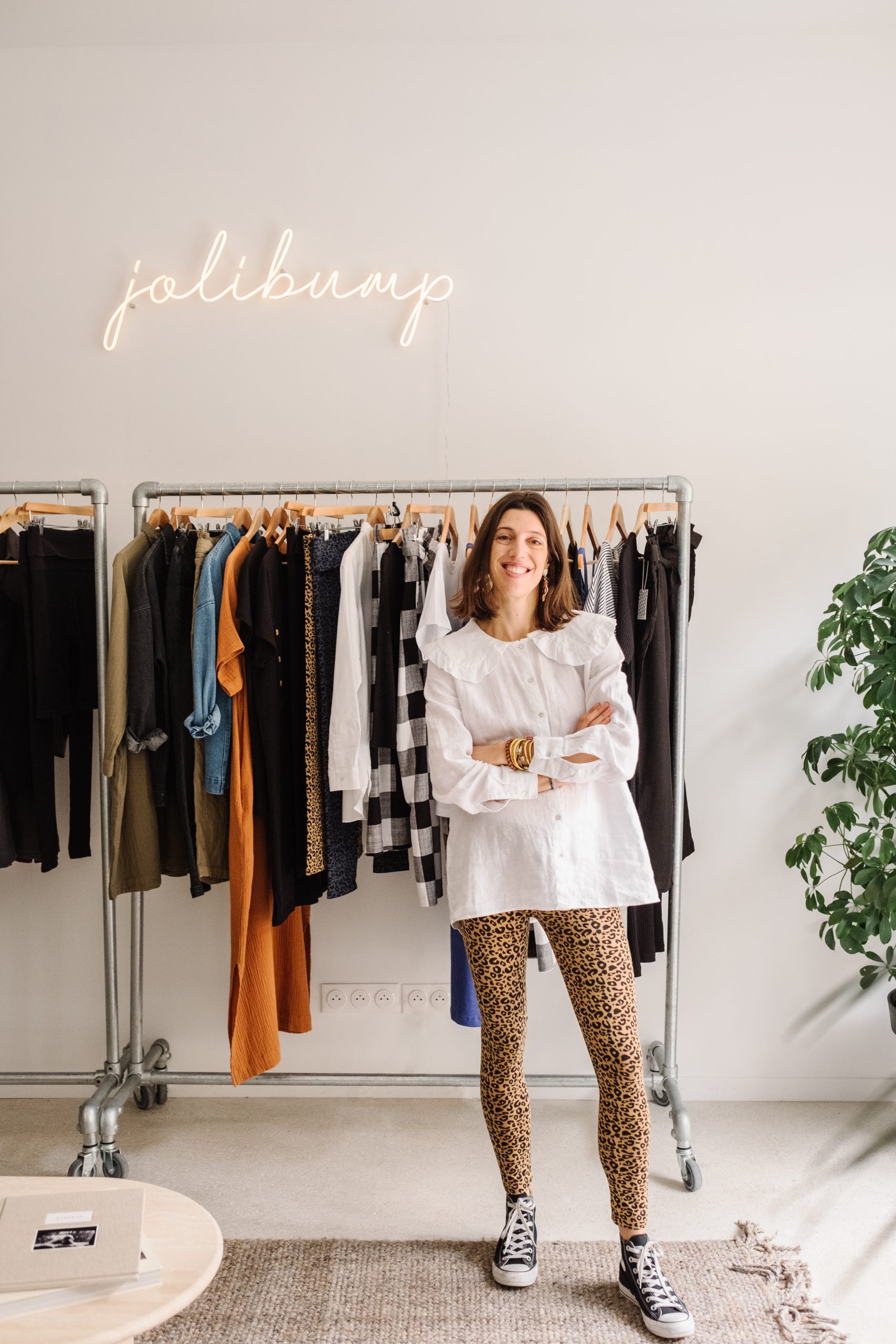 Marie Boyer-Aubert devant un portant de vêtements de maternité durable dans la boutique Jolibump.