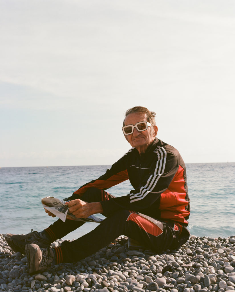 Homme assis devant la mer et portant des lunettes de la jeune marque Musu.
